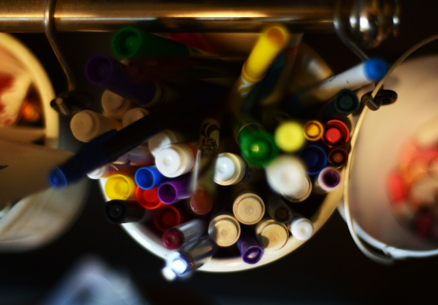 Markers and pencils are crammed into a metal bucket
